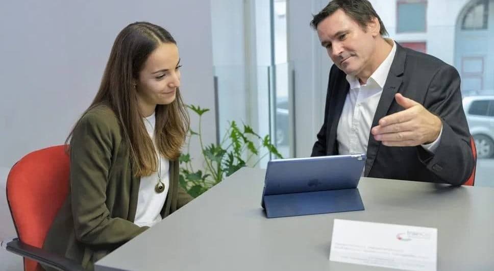 Beratungsgespräch am Tisch, gemeinsamer Blick auf ein Tablet
