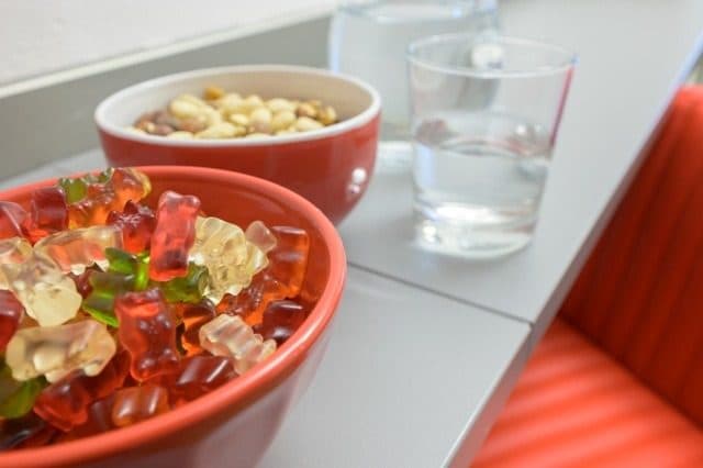 Rote Schalen mit Süßigkeiten und Nüssen, daneben ein Wasserglas