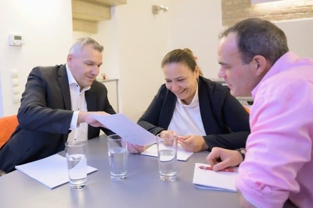 Drei Personen besprechen Unterlagen am Besprechungstisch