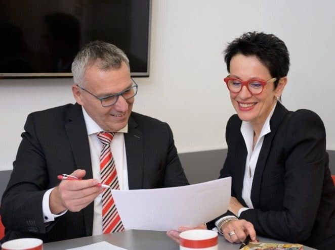 Beraterin und Berater im Gespräch, vor ihnen ein Blatt Papier