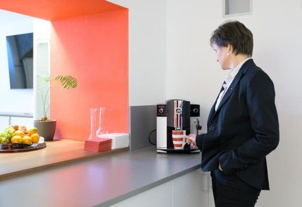 Person holt sich Kaffee am Automaten in der Küche