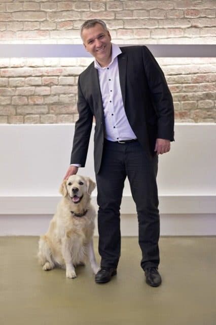 Geschäftsführer steht im Seminarraum, der Hund sitzt neben ihm