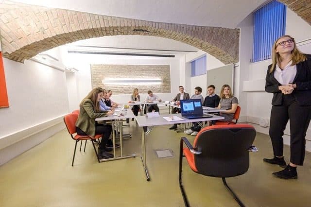 Trainerin am rechten Bildrand, Blick über die Seminargruppe
