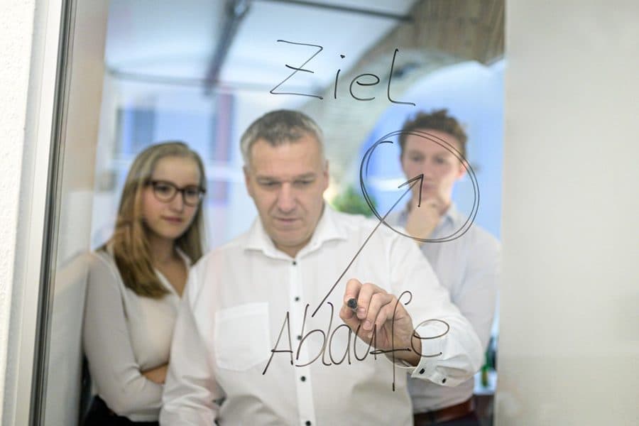 Teilnehmende ergänzen Abläufe auf der Glaswand